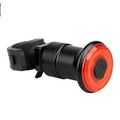 Luz trasera inteligente negra de plástico, con lente circular roja y soporte de goma para bicicleta.