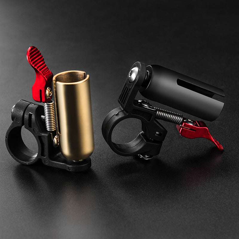 Timbre minimalista de latón dorado con soporte negro y palanca roja, de diseño compacto para bicicleta.